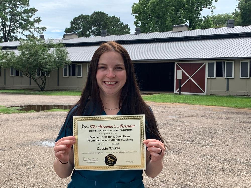 Cassie poses with a certificate marking her completion of equine ultrasound training. 